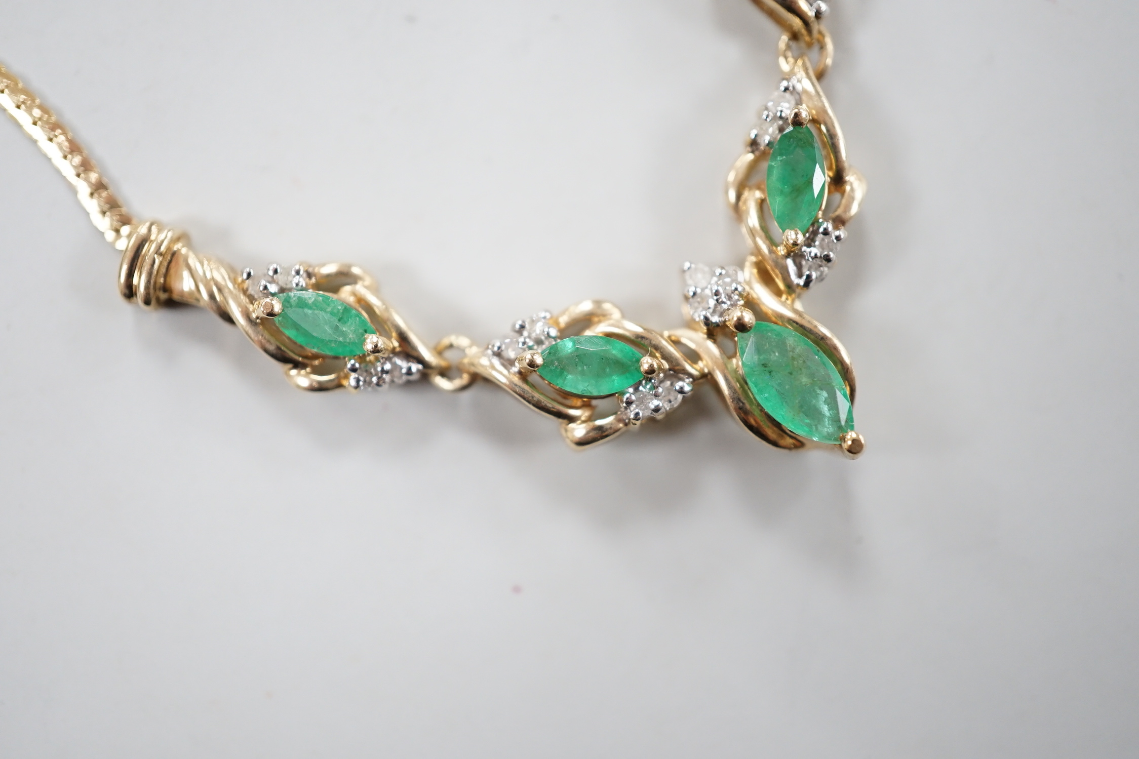 A modern 9ct gold, five stone marquise cut emerald and diamond chip cluster set necklace, 46cm, gross weight 6.2 grams.